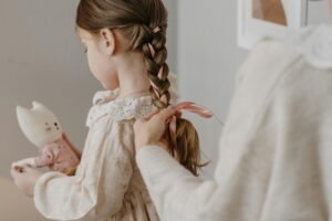 A serene moment as a mother braids her daughter's hair, creating a warm and intimate family setting.